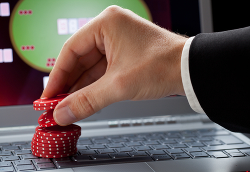 joueur plaçant des jetons de casino sur un ordinateur portable affichant un casino en ligne